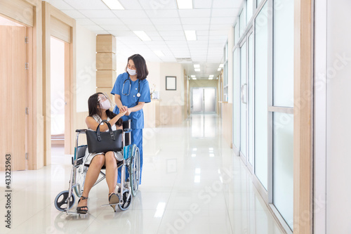 Asian patient on hospital wheelchair discussing with female doctor. Doctors are encouraging sick people during Covid 19.