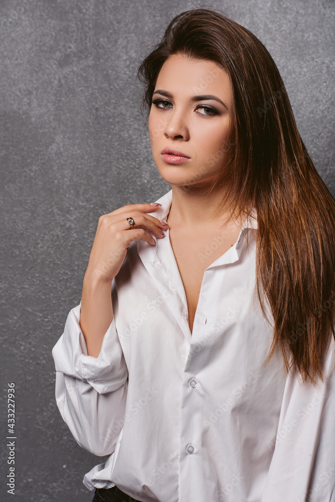 Sexy girl. Close up portrait of a glamorous very beautiful brunette girl with loose hair in the studio on a gray background who looks at the floor. Portrait of a girl 18-27 years old Sexy girl. Close up portrait of a glamorous very beautiful brunette girl with loose hair in the studio on a gray background who looks at the floor. Portrait of a girl 18-27 years old
