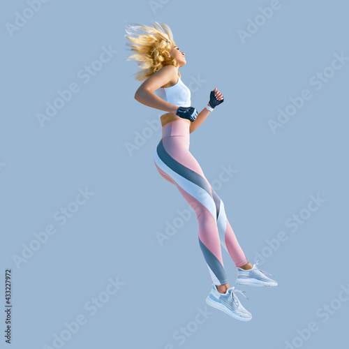 Fototapeta Naklejka Na Ścianę i Meble -  Profile picture of energetic inspired caucasian female in sportswear running and jumping, isolated along plain background. Motivation fitness concept photo