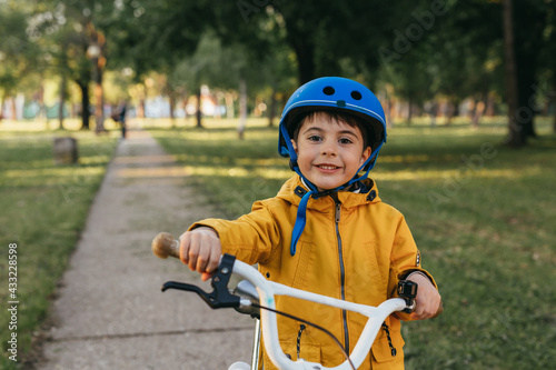 cute little boy posing with his bike in public park