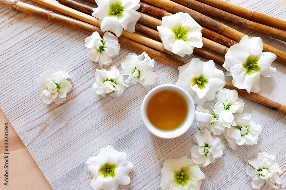 Chinese herbal tea in white cup, brown bamboo and white flowers on wooden table with copy space. Top view. Chinese herbal tea in white cup, brown bamboo and white flowers on wooden table with copy space. Top view.