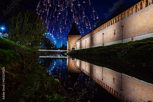 volleys of festive fireworks are reflected in the water. salute to the city holiday. beautiful view of the pond and the old fortress under the fireworks flashes photo