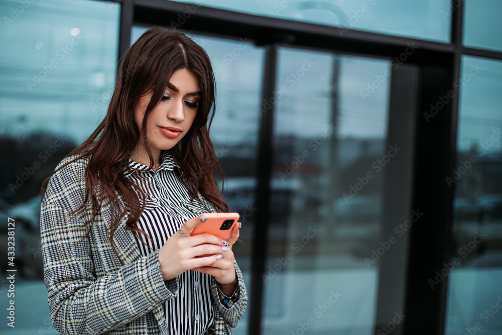 Small business owner office worker woman standing outside building with mobile phone make selfie video chat. Female mexican latin american successful executive girl hold gadget