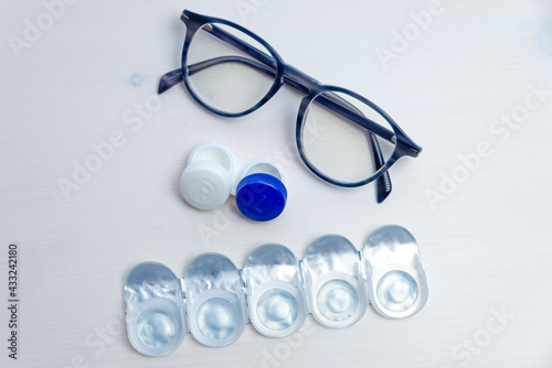 Contact lenses  contact lens packaging and lens container  on white surface. Vision correction and the alternative between glasses and contact lenses.  