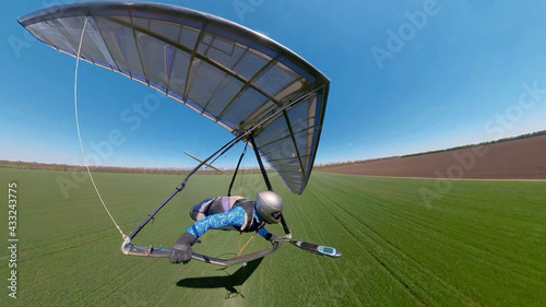 Hang glider pilot approaches landing on the green grassy field. photo