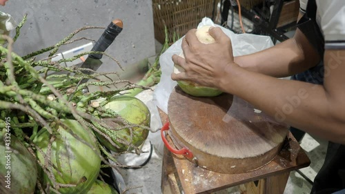 Peeling Thai coconut skin in the traditional way. Which keeping coconut skin and water fresh inside. Young coconut peeled by hand. Thailand Local style of peeling coconut. Asian famous food and drink