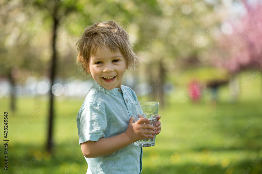 Beautiful blond child, boy, drinking water in the park on a hot day Beautiful blond child, boy, drinking water in the park on a hot day
