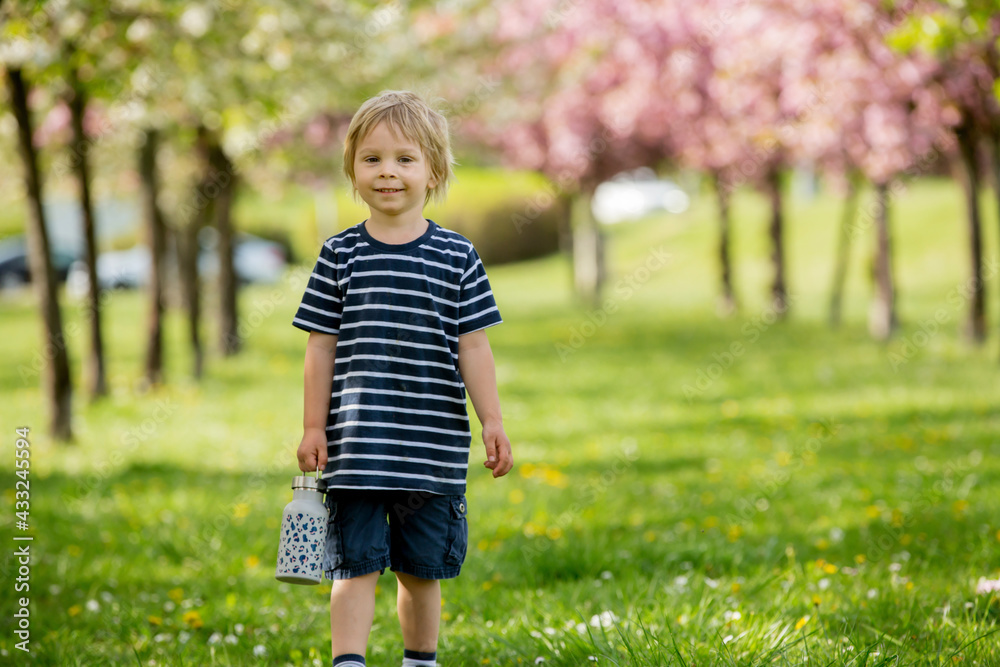 Beautiful blond child, boy, drinking water in the park on a hot day Beautiful blond child, boy, drinking water in the park on a hot day