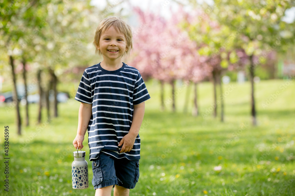 Beautiful blond child, boy, drinking water in the park on a hot day Beautiful blond child, boy, drinking water in the park on a hot day