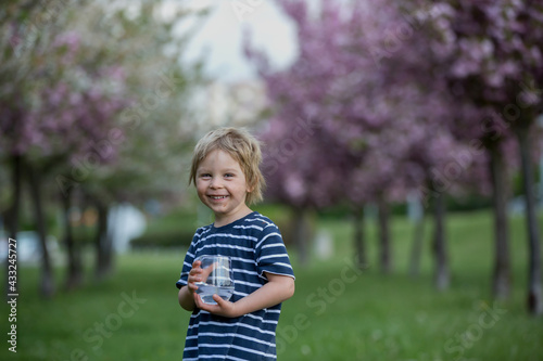 Beautiful blond child, boy, drinking water in the park on a hot day