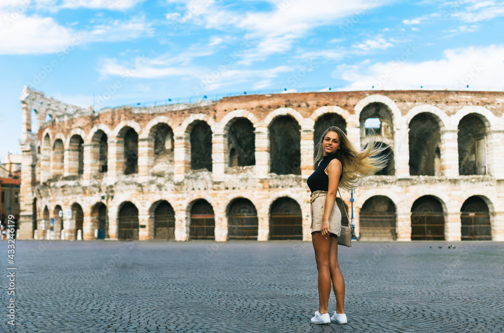 Beautiful young girl tourist looking and smiling at camera. The amphitheater of verona