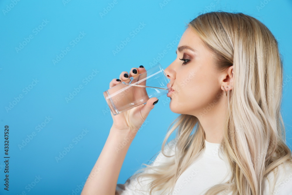 young woman drinking water on blue background. girl holding a glass of water young woman drinking water on blue background. girl holding a glass of water