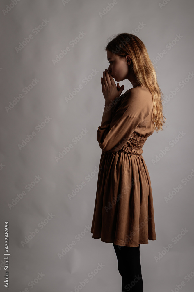 Fototapeta premium Woman in brown is having a heartache. Depression and sadness. Prayer.