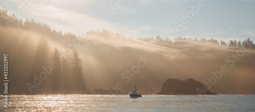 Canvas Print Atmospheric golden light sunbeams through morning mist and fog over an ocean fishing boat off the pacific coast of Vancouver Island near Port Renfrew, BC, Canada