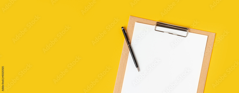 Top view of the blank white paper on the cardboard notepad for your notes to remember on the yellow background with a free space Top view of the blank white paper on the cardboard notepad for your notes to remember on the yellow background with a free space