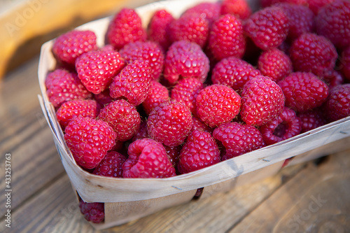 Fresh sweet juicy raspberries in a wooden basket close-up on a wooden table.