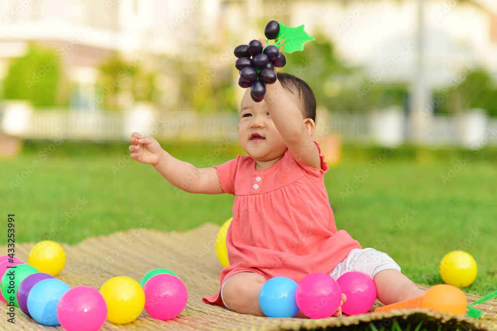Obraz premium Cute Asian baby girl playing with toys in playground