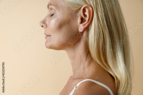 Wallpaper Mural Cropped portrait of natural mature blonde woman in white underwear posing with eyes closed, standing isolated over beige background Torontodigital.ca