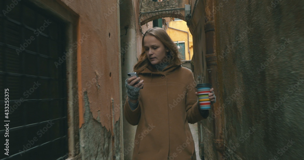 Woman with phone and coffee walking in Venice Woman with phone and coffee walking in Venice