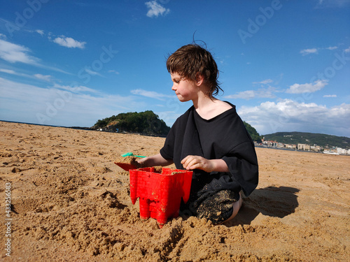 Niño jugando con arena en la playa de San Sebastián photo