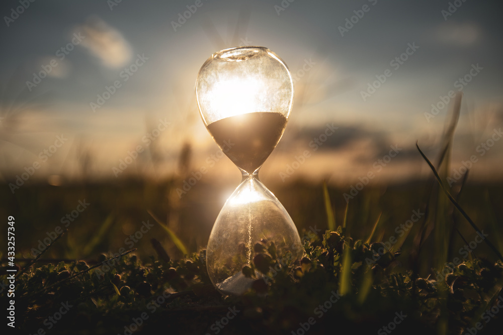 Life time passing concept. Hourglass at sunset time. concept time is money. - obrazy, fototapety, plakaty 