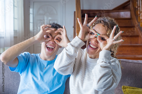 Billede på lærred Portrait of happy grown-up teenager man posing with mother have fun at home toge