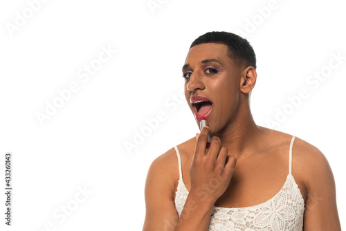 Fotografie african american transvestite man in sundress looking at camera whle applying li