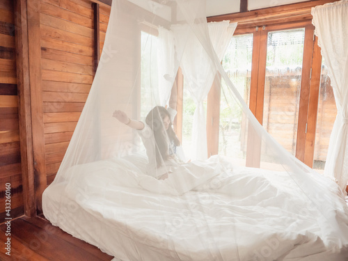 Woman stretching in bed after wake up, Happy greets new day with warm sunlight.