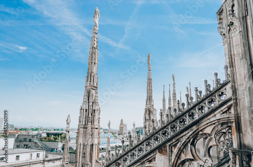 Roof of Milan Cathedral Duomo di Milano with Gothic spires and white marble statues. Top tourist attraction on piazza in Milan, Italy.