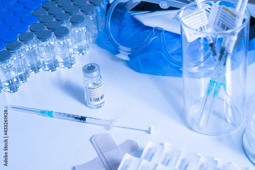 Glass bottle vial and syringe with Covid-19 Coronavirus vaccine in a research medical facility lab. Ampoules with cure on the medical worker laboratory table. Sars-cov-2 pandemic concept. Glass bottle vial and syringe with Covid-19 Coronavirus vaccine in a research medical facility lab. Ampoules with cure on the medical worker laboratory table. Sars-cov-2 pandemic concept.