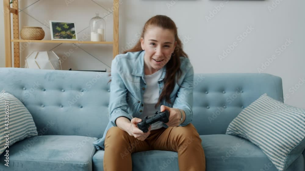 Portrait of carefree young woman playing video game losing throwing joystick sitting on sofa at home. Modern technology and entertainment concept. Portrait of carefree young woman playing video game losing throwing joystick sitting on sofa at home. Modern technology and entertainment concept.