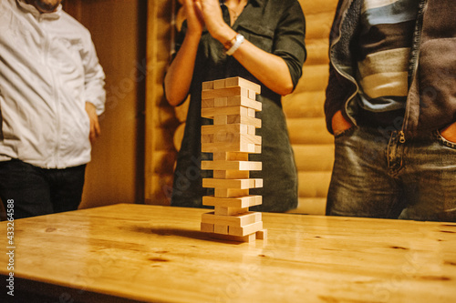 Wooden stick tower Board game, a group of young friends play wooden stick tower Board game, a great pastime, peaceful games develop people, a tower of sticks stands on a wooden table