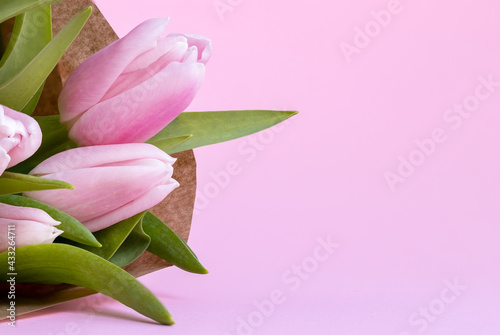 Fototapeta Naklejka Na Ścianę i Meble -  Beautiful delicate bouquet of tulip flowers in craft wrapping paper on pink background with copy space