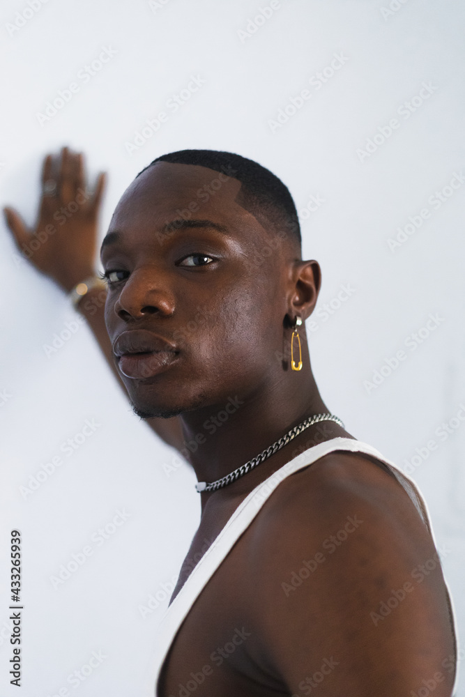 Man with hand placed on white wall.