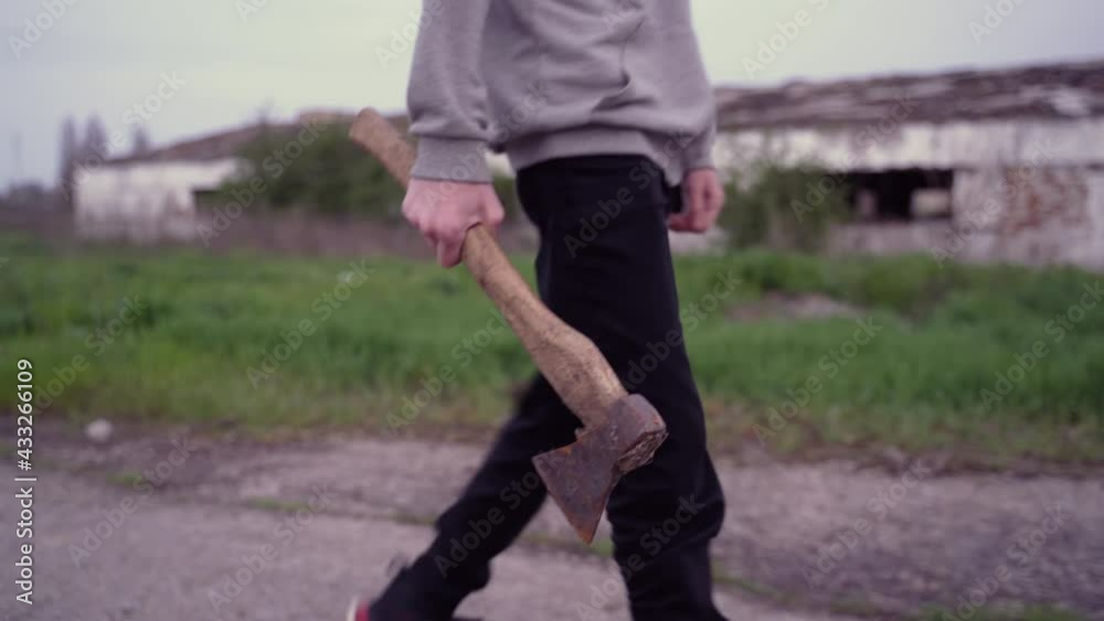 Teenager walks with an ax along the old road Teenager walks with an ax along the old road