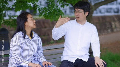 公園のベンチで手話を使って会話をしているカップル