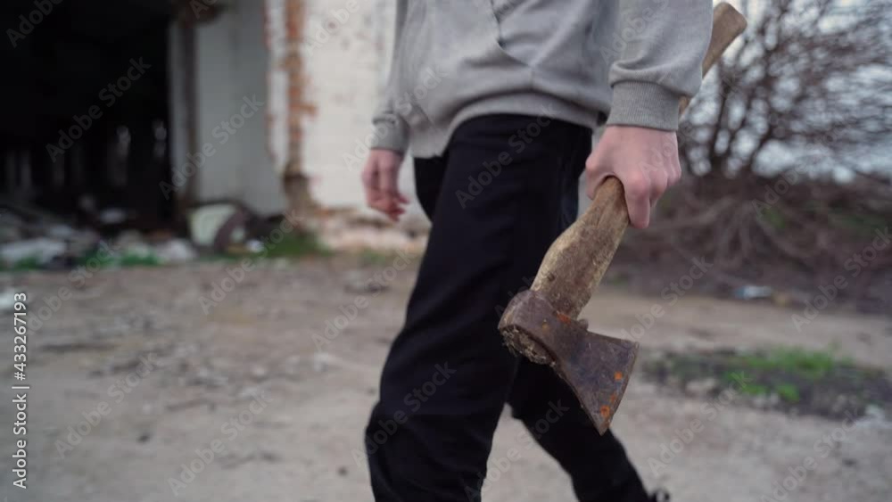 Teenager walks with an ax along the old road Teenager walks with an ax along the old road