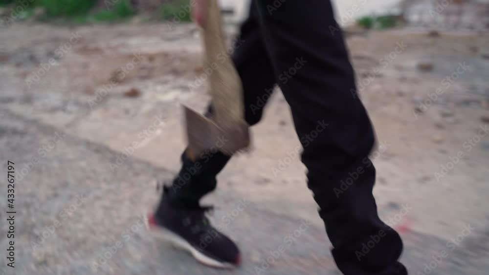 Teenager walks with an ax along the old road Teenager walks with an ax along the old road