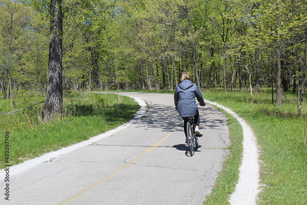 Woman on a bicycle heading into a turn on the North Branch Trail at Miami Woods in Morton Grove, Illinois