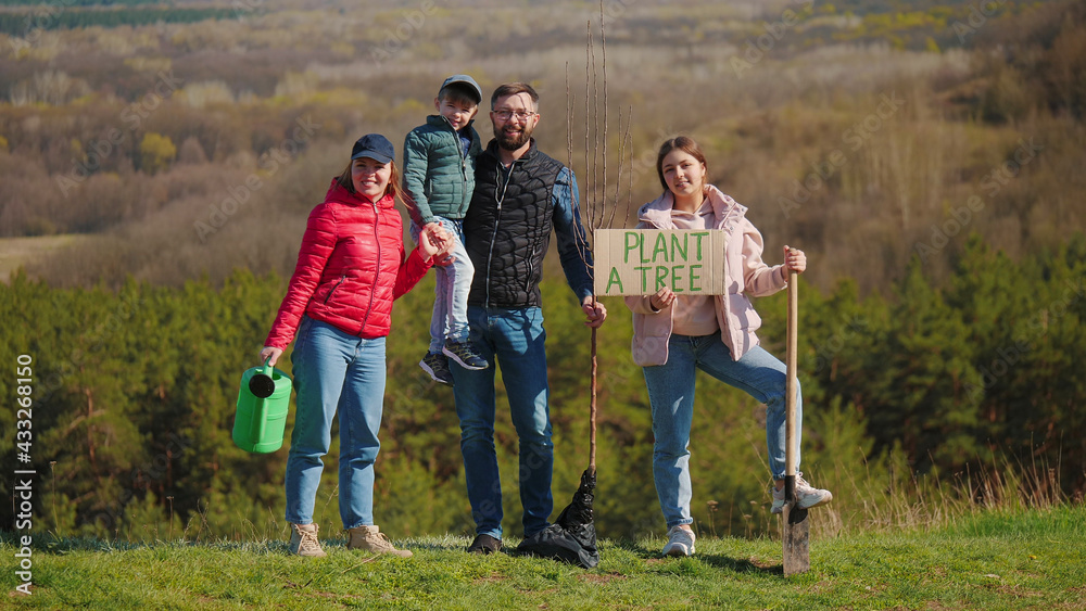 Portrait of a family of volunteers with children before planting a tree in nature
