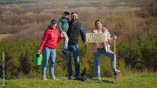 Portrait of a family of volunteers with children before planting a tree in nature