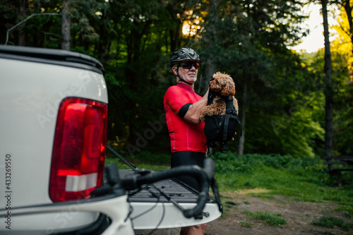 Male cyclist and his puppy ready for bike tour in forest