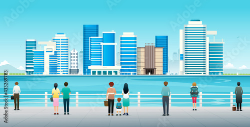 People and tourists are watching the cityscapes next to the sea.