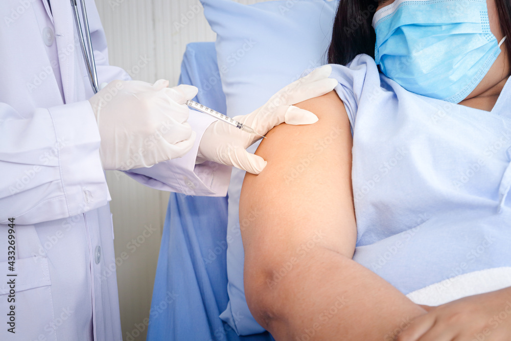 Doctors wear gloves to vaccinate obese women who wear masks to prevent the coronavirus. To build immunity. Hospital medical service concept Doctors wear gloves to vaccinate obese women who wear masks to prevent the coronavirus. To build immunity. Hospital medical service concept