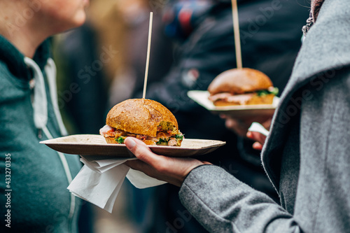 hand holding street food burger on paper plate