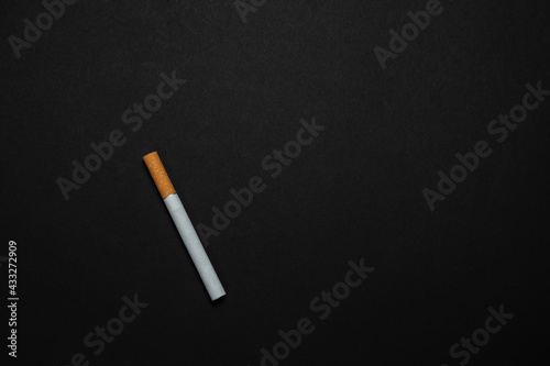 A Cigarette with Yellow filter on a black background.