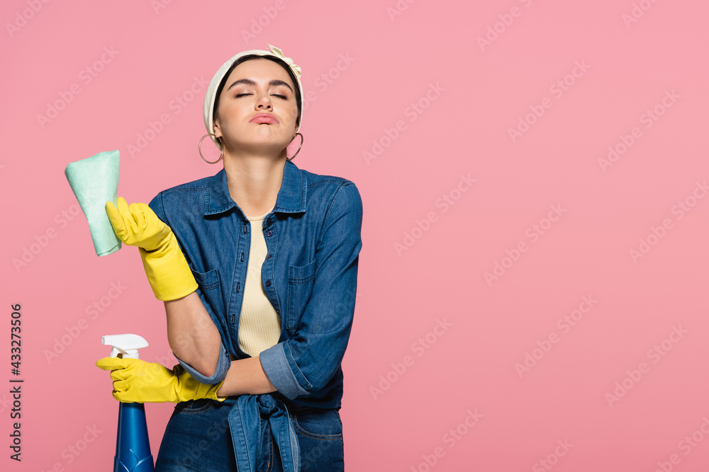 Tired housewife with rag and detergent isolated on pink Tired housewife with rag and detergent isolated on pink