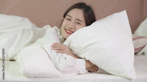 Happy girl hug pillow on bed and smile at home in the morning