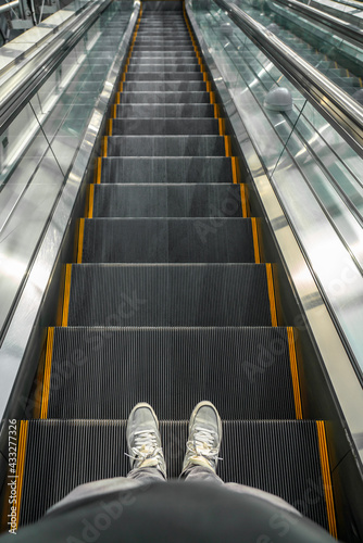 Man Wearing Nike Sneakers Going Down an Escalator