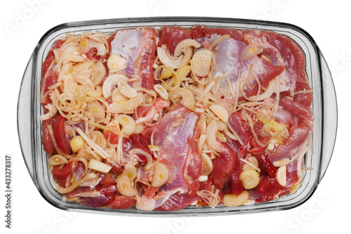 Raw meat with onions and spices on a glass baking tray. Isolated on a white background, top view